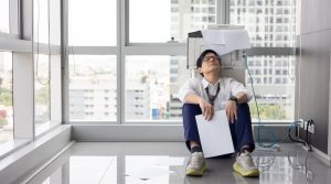 frustrated man sitting beside broken copier