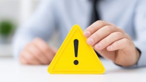 A warning sign held by person in business attire, symbolizing caution and alertness in professional environment